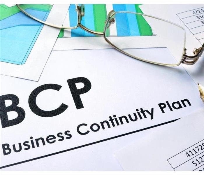Paper with words BCP Business Continuity Plan and there is a pen and pair of glasses on top of the paper